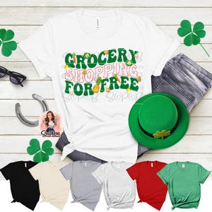 May include: A white t-shirt with the text "GROCERY SHOPPING FOR FREE" in green and orange. The image includes a green hat, shamrocks, and a variety of t-shirts in different colors, including black, beige, gray, red, and green.