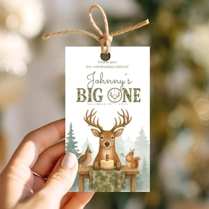May include: A rectangular gift tag with a watercolor illustration of a deer, bird, and squirrel celebrating a birthday. The tag reads "Johnny's BIG ONE" with the date. A twine bow is at the top.