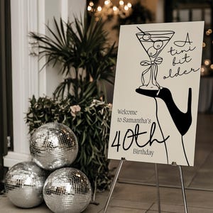Letrero de bienvenida de cumpleaños editable con la frase "A Tini Bit Older", letrero decorativo minimalista dibujado a mano con temática de martini, lazos en blanco y negro