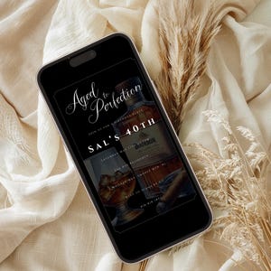 Peut inclure: Un &eacute;cran de smartphone noir affichant une invitation &agrave; une f&ecirc;te d'anniversaire avec le texte "Aged to Perfection" et "Sal's 40th". L'invitation pr&eacute;sente une bouteille de bourbon et un verre de whisky.