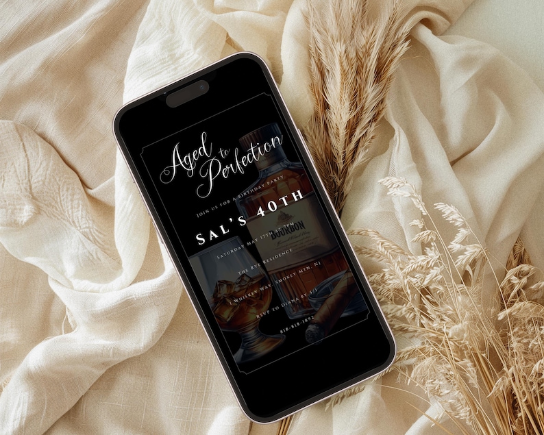 Peut inclure: Un &eacute;cran de smartphone noir affichant une invitation &agrave; une f&ecirc;te d'anniversaire avec le texte "Aged to Perfection" et "Sal's 40th". L'invitation pr&eacute;sente une bouteille de bourbon et un verre de whisky.