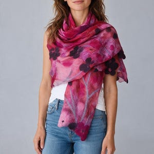May include: A lightweight rectangular scarf featuring a vibrant magenta and pink gradient background with dark purple felted floral accents and light gray branch-like patterns. The scarf has a soft, semi-sheer texture and draped design.