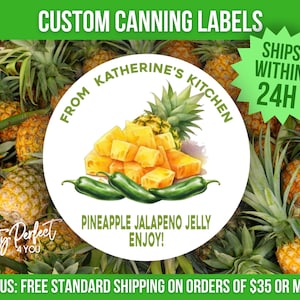 May include: White round label with the text "From Katherine's Kitchen" and "Pineapple Jalapeno Jelly Enjoy!"  The label features a watercolor illustration of pineapple chunks and jalapeno peppers. The label is surrounded by pineapples.