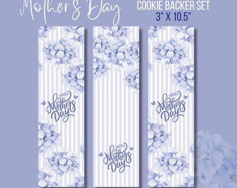 May include: A set of three cookie backer sheets with a floral design. The sheets are 3 inches by 10.5 inches and feature a watercolor-style design of blue hydrangeas with a white striped background. The text "Happy Mother's Day" is written in purple on each sheet.