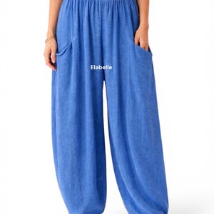 May include: Bright blue loose-fitting trousers with an elasticized waistband and two side pockets. The word Elabelle is printed in white on the front of the pants. These wide-leg pants feature a gathered hem design and a textured fabric finish.