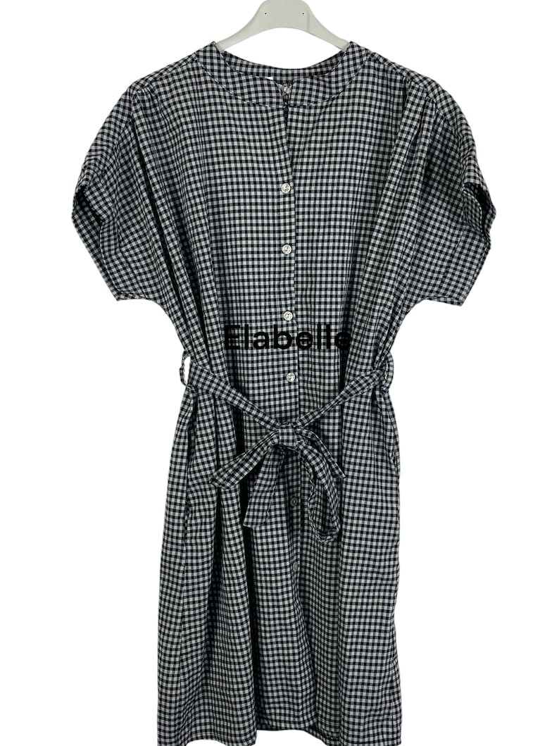 May include: A black and white gingham dress with short sleeves and a button-down front. The dress features a matching belt tied at the waist and the word "Elabelle" printed on the front.
