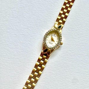 Reloj ELGIN &quot;La Heredera&quot;, de los años 90, con ónix, talla marquesa ovalada y detalles de diamantes, para mujer, de cuarzo, en tono dorado.