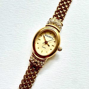 Reloj ELGIN &quot;The Starlet&quot; de los años 90 con pulsera de cuarzo ovalada, malla dorada y detalles de diamantes