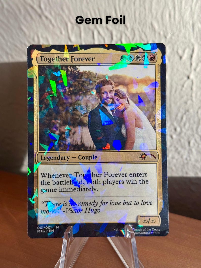 K&ouml;nnte beinhalten: Eine individuelle Sammelkarte mit dem Titel Together Forever und einer Gem-Foil-Oberfl&auml;che. Die Karte zeigt ein Foto eines Paares in Hochzeitskleidung, den Text Legendary - Couple und das Zitat There is no remedy for love but to love more von Victor Hugo.