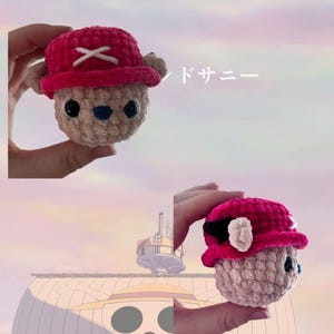 May include: Crocheted plush toy of a character with a pink hat and a white cross on it. The toy has a beige body, black eyes, and a blue nose. The ears are beige. The toy is held in a hand.