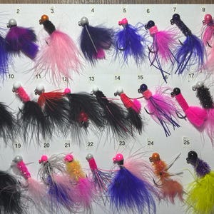 May include: A collection of 25 colorful fishing lures with feathers and beads. The lures are numbered 1 through 25.