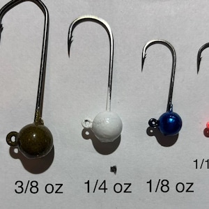 May include: Six fishing jig heads with different colored beads and weights. The weights are 1/2 oz, 3/8 oz, 1/4 oz, 1/8 oz, 1/16 oz, and 1/32 oz.