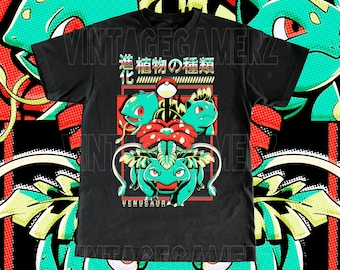 May include: Black t-shirt featuring a colorful graphic of a Venusaur evolution line. The design includes the text "VINTAGEGAMERZ" and Japanese text. The background has a repeating pattern of green and red elements.