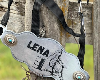 Könnte beinhalten: Ein silbernes Lederhalfter mit einem Türkis-Stein-Design und dem eingravierten Namen "LENA". Das Halfter zeigt eine Schwarzweiß-Illustration eines Barrel-Racers auf einem Pferd.