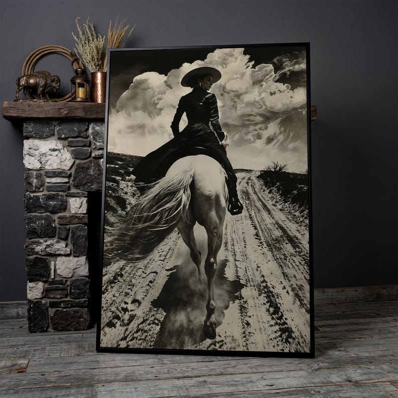May include: Black and white framed print of a person riding a white horse on a dirt road. The person is wearing a hat and long coat. The sky is filled with dramatic clouds. The print is displayed on a wooden floor.
