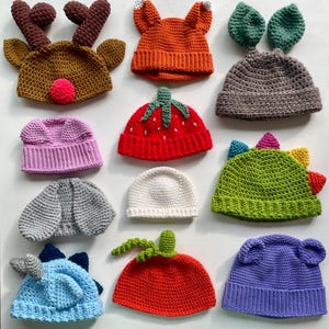 Puede incluir: Una colección de sombreros de ganchillo hechos a mano en varios colores y diseños. Los sombreros incluyen estilos con temas de animales como un reno, un zorro, un conejito y un dinosaurio. Otros sombreros están diseñados para parecerse a una fresa y un tomate.