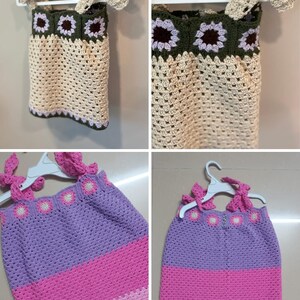 May include: A cream, green, and purple crocheted top. The top has a floral pattern around the neckline and straps. It is displayed on a white hanger.