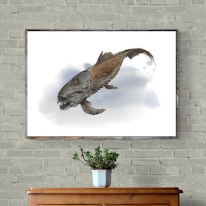 May include: A framed watercolour painting of a Dunkleosteus fish, a prehistoric armoured fish, set against a soft blue and white background. The artwork is displayed on a wooden surface.