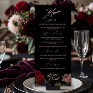 May include: A black menu card with a floral design and gold accents, displayed on a white plate with a gold rim. The menu lists starters, main courses, desserts, and beverages. The text "Victoria David" is at the bottom.