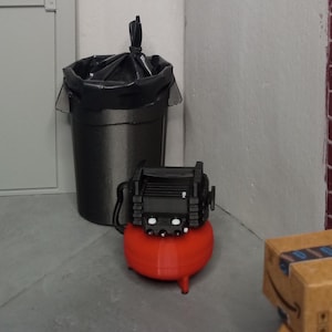 May include: A red air compressor with a black top and a black trash can with a black plastic bag in the background.