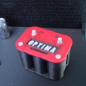 May include: A red car battery with the word "OPTIMA" printed on the top. The battery has black terminals and is made of plastic.