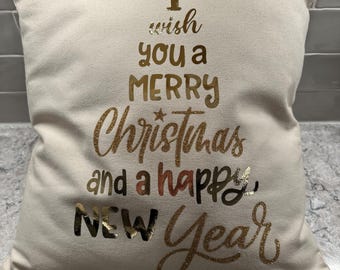 May include: A white throw pillow with gold glitter lettering that reads "I wish you a Merry Christmas and a Happy New Year".