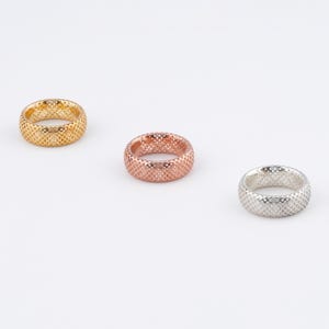 May include: Three gold, rose gold, and silver rings with a textured, woven design.