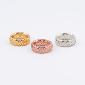 May include: Three gold, rose gold, and silver rings with a textured, geometric design.