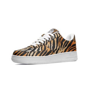 May include: A single sneaker with a tiger stripe pattern in orange and black. The shoe has a white sole and white laces. The sneaker is a low-top style.