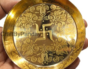 May include: A round, gold-colored metal plate with an engraved floral design and a central Swastika symbol. The plate has a raised edge and a polished finish. The text "CraftByPanday" is visible on the left side.