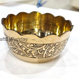 May include: A brass bowl with a scalloped edge and etched floral pattern. The interior is gold, and the exterior has a matte finish. The text "CraftByPanday" is visible on the side of the bowl.
