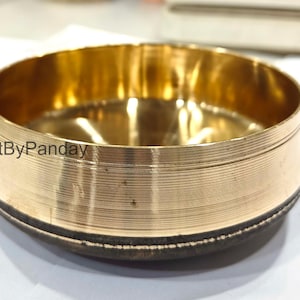 Peut inclure: Un bol rond en laiton avec une large bande texturée au milieu. L'intérieur du bol est de couleur or brillant. Le texte "CraftByPanday" est visible sur le côté du bol.
