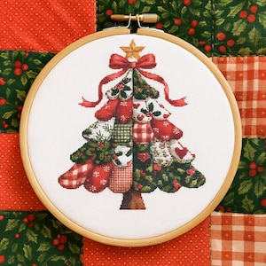 Könnte beinhalten: Ein Kreuzstich-Weihnachtsbaum-Design in einem hölzernen Stickrahmen. Der Baum besteht aus verschiedenen rot-, grün- und weiß gemusterten Stoffen, gekrönt von einer roten Schleife und einem goldenen Stern. Der Hintergrund ist ein Patchwork aus rotem und grünem Stoff.