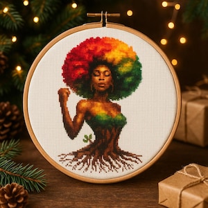 May include: A cross-stitch embroidery of a woman with a vibrant afro in red, yellow, and green. Her body transitions into a tree trunk with roots. The artwork is framed in a round wooden hoop, showcasing a unique blend of nature and artistry.