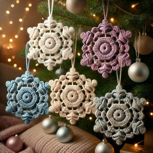 May include: Five crocheted snowflake ornaments in various colors, including white, light blue, light purple, and cream, hanging on a Christmas tree.