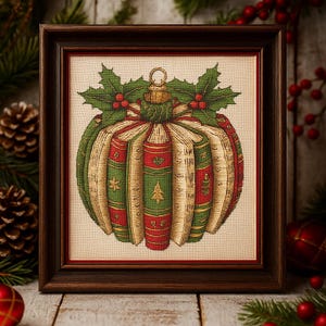May include: Cross-stitch art in a dark brown frame. The artwork depicts a Christmas ornament made of books, with red and green spines. Holly and berries adorn the top. The ornament is on a cream-colored background.