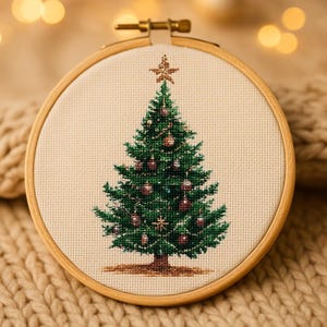 May include: A cross-stitch embroidery of a Christmas tree, displayed in a wooden hoop. The tree is green with ornaments and a star on top. The background is a neutral fabric, and the hoop is held by a brass clasp.