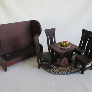 May include: Miniature wooden dining set with a bench, table, and three chairs. The set is stained a dark reddish-brown color. A small bowl of fruit sits on the table, which is placed on a small rug.