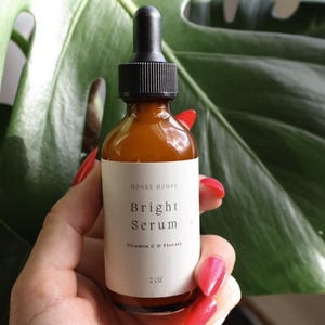 May include: A brown glass bottle with a dropper top, labeled "Honey House Bright Serum Vitamin C & Florals 2oz".