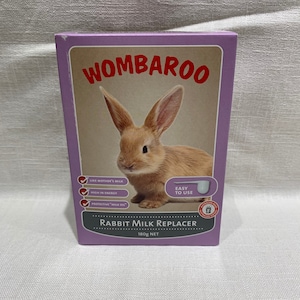 May include: A purple box with a picture of a brown rabbit on the front. The box is labeled "WOMBAROO RABBIT MILK REPLACER 180g NET". The box also has a list of features, including "Like Mother's Milk", "High in Energy", and "Protective "Milk Oil"".