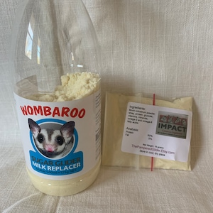 May include: A clear plastic bottle with a white label that says "WOMBAROO Sugar Glider Milk Replacer Makes 500ml - 125g NET". The bottle is filled with a white powder. A small white bag with a red label that says "IMPACT" is next to the bottle. The label on the bag lists the ingredients and analysis of the powder. The bag says "Net Weight: 16 grams ThePamperedGlider.Etsy.com Store in cool, dry place."