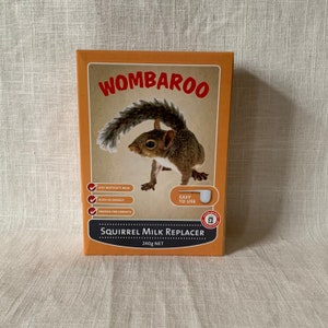 May include: A brown box with a squirrel illustration and the text "WOMBAROO SQUIRREL MILK REPLACER 240g NET". The box has a checklist with the text "LIKE MOTHER'S MILK", "HIGH IN ENERGY", and "PROTEIN FOR GROWTH". The box also has a white scoop and the text "EASY TO USE".