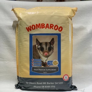 Può includere: Un sacchetto giallo di Wombaroo High Protein Supplement per lo scivolo dello zucchero. Il sacchetto presenta un'immagine di uno scivolo dello zucchero e il testo "Wombaroo High Protein Supplement 5kg NET". Il sacchetto include anche le informazioni di contatto dell'azienda: 10 Oborn Road Mt Barker SA 5251, Phone 08 8391 1713, www.wombaroo.com.au.