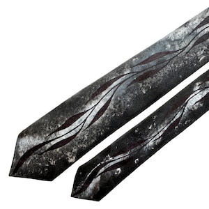 May include: Two dark grey neckties with a distressed, textured appearance. Each tie features a repeating pattern of dark red, leaf-like designs against a lighter grey and white background. The ties are angled, showcasing their pointed ends.
