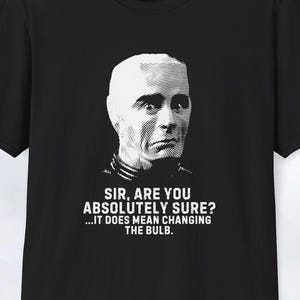 Peut inclure: T-shirt noir avec un portrait blanc d'un homme et le texte "SIR, ARE YOU ABSOLUTELY SURE? ...IT DOES MEAN CHANGING THE BULB." Le t-shirt est de style col rond.
