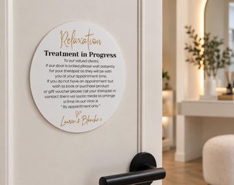 May include: A circular white sign mounted on a door with black and gold text that reads: Relaxation Treatment in Progress. To our valued clients, if our door is locked please wait patiently for your therapist. By appointment only. Lauren & Blanche.