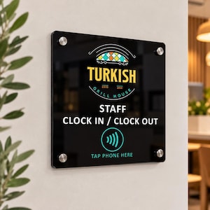 Puede incluir: Un letrero rectangular de acrílico negro con herrajes plateados. Presenta el texto TURKISH GRILL HOUSE ESTD 2004, STAFF CLOCK IN / CLOCK OUT y un icono de contacto con el texto TAP PHONE HERE en colores blanco y turquesa.