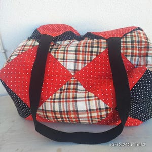 Puede incluir: Una bolsa de mano de lona roja, negra y blanca con correas negras. La bolsa está hecha de diferentes telas, incluyendo cuadros y lunares.