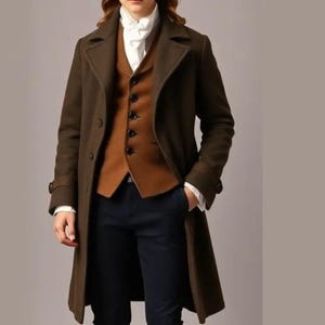 May include: A brown overcoat, vest, and breeches ensemble. The long coat is buttoned and worn over a brown vest and a white collared shirt. The outfit includes dark blue breeches, brown socks, black shoes, and a black hat. The clothing is a historical costume.