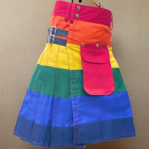 May include: A rainbow kilt with a red pocket and a black leather belt. The kilt is made of a thick, durable fabric and has a traditional design.